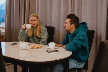 A young man and his female friend chat over tea in a cozy kitchen. Authentic moment of casual conversation and friendly connection in everyday setting