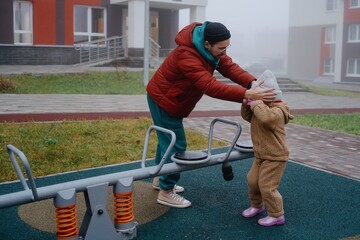 A young father plays with his 4-year-old daughter on a sunny playground, capturing authentic moments of paternal love and joyful family bonding