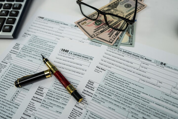 US dollar bills and form 1040 with glasses and calculator ready for 2026 tax processing