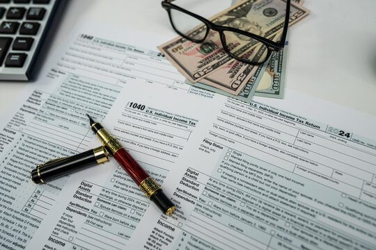 US dollar bills and form 1040 with glasses and calculator ready for 2026 tax processing