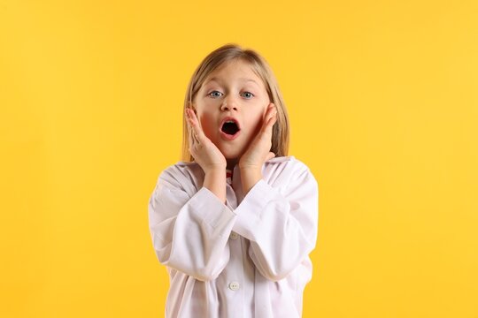 Portrait of surprised little girl in laboratory coat on yellow background. Child and science