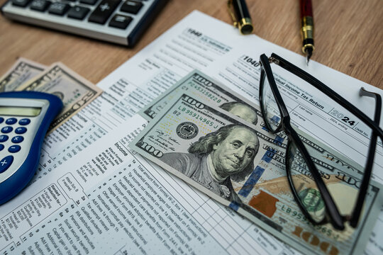 Form 1040 with US dollar bills, glasses and calculator for 2025 tax filing