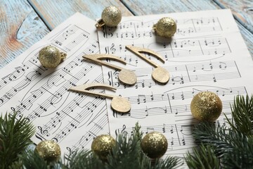Golden music notes, sheets and Christmas decor on wooden table, closeup