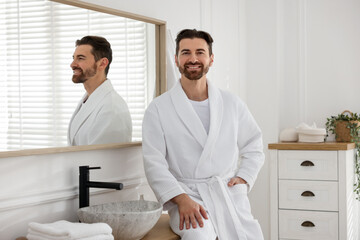Handsome man wearing white bathrobe in bathroom