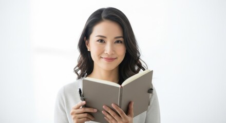 Fototapeta premium Confident young woman smiling while reading a notebook in a bright modern space