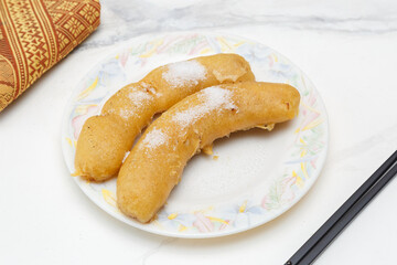 Beignets de bananes frits saupoudrés de sucre sur assiette blanche. Cuisine chinoise. Traiteur chinois.