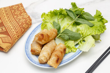 Nems au porc sur assiette blanche avec feuille de menthe et salade. Cuisine thaïlandaise. Traiteur thaï.