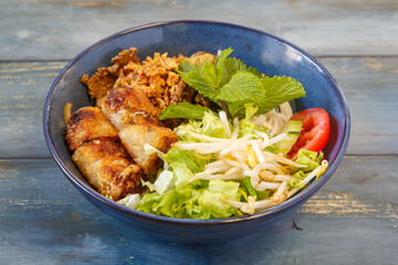Bo Bun au poulet dans un bol bleu, cuisine vietnamienne, fond bleu rustique