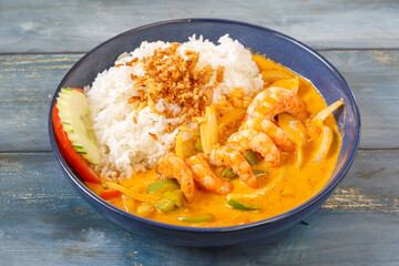 Crevettes au curry rouge thaï dans un bol bleu, cuisine thaïlandaise, fond bleu rustique
