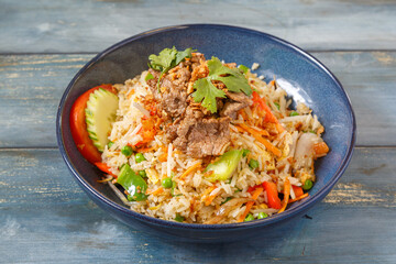 Khao Pad au bœuf dans un bol bleu, cuisine thaïlandaise, fond bleu rustique