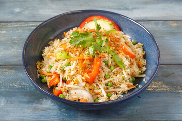 Khao Pad nature avec oignons, pousses de soja, carottes et coriandre dans un bol bleu, cuisine thaïlandaise, fond bleu rustique © Lina Taravella