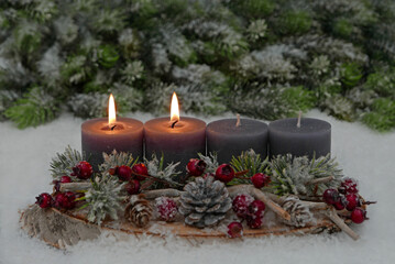 Second Advent: Decoration with grey candles, fir branches, cones and berries on a tree slice decorated with space for text in the background.