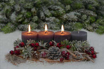 Third Advent: Decoration with grey candles, fir branches, cones and berries on a tree slice decorated with space for text in the background.