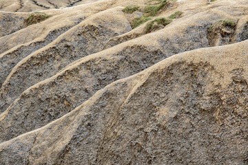 a dry, arid landscape featuring undulating, sandy hills with a textured surface of small, coarse pebbles and sparse patches of grass