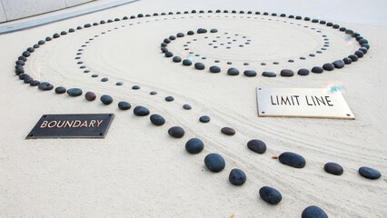 Meticulously Arranged Dark Obsidian Stones Form a Spiral Pattern in a Zen Garden