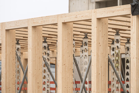 Close-up view of a timber construction site showing vertical wooden beams and metal support props arranged in repeating structural patterns