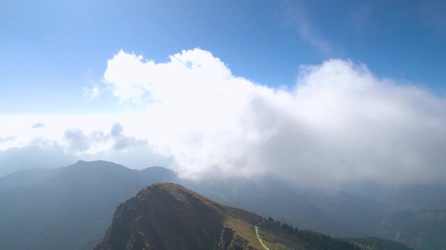 Aerial drone shot quick pan from himalaya mountains with cloud cover hiding snow covered Annapurna peaks in the distance in Nepal showing the beauty of Uttarakhand India