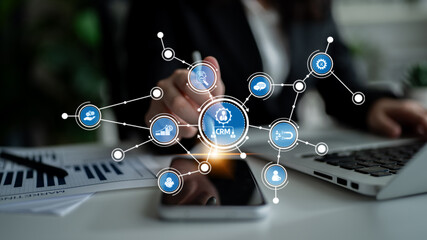 Businesswoman interacts with smartphone while various CRM icons and data analytics graphics float in a modern office, symbolizing digital connectivity and efficiency. Tessel