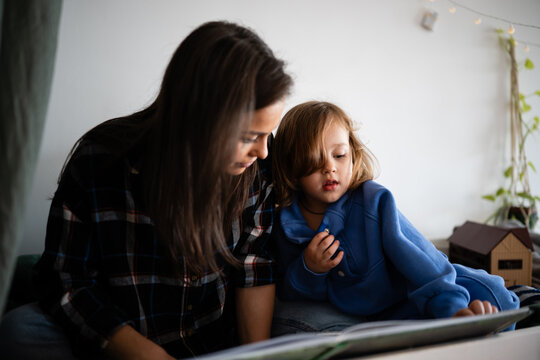 Mother and child reading book together at home