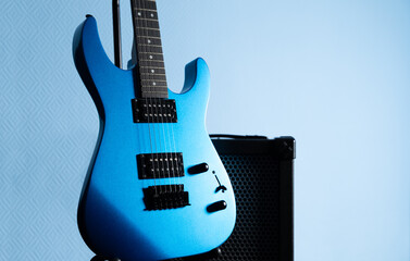 Obraz premium Blue Electric guitar with amplifier on light blue background. Music instruments with copy space for text or advertising design.