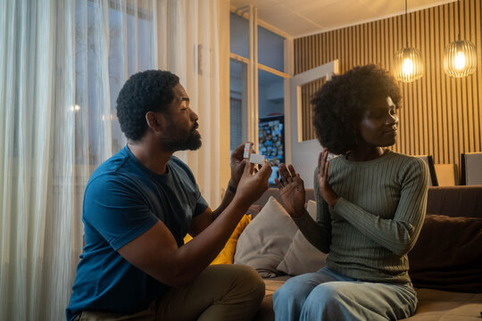 Romantic proposal rejected, black man asks girlfriend in living room at night - Powered by Adobe