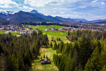 Scenic view of Giewont mountain and Zakopane (Cyrhla district) in the Polish Tatra Mountains. Lush green slopes and residential houses on a sunny day.
