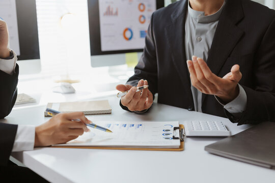 Business team reviewing financial reports with charts, discussing marketing strategy and company performance in an office setting