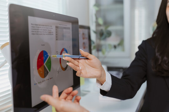 Businesswoman presenting financial data and market share analysis on an interactive computer screen during an office meeting