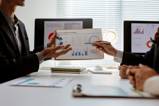 Business professionals collaborating, discussing financial charts and data during an office meeting, focusing on strategic planning and analysis
