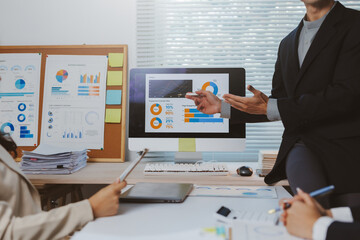 Business team members collaborating and presenting financial data on a monitor during an office meeting, focusing on analytics and growth