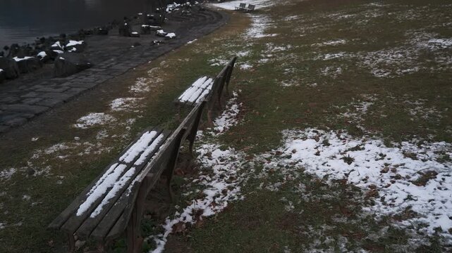 薄っすらと雪が被った湖畔の公園ベンチ