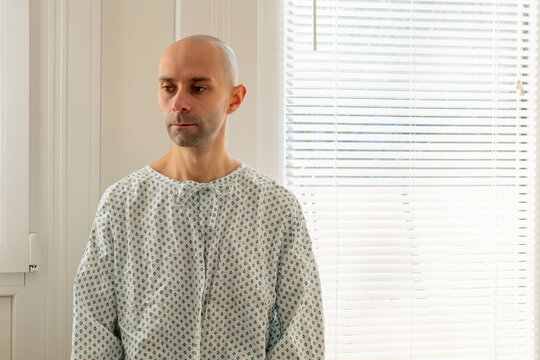 bald male patient in hospital, man in standard issue hospital gown, expression anxiety and worry before surgery or a critical diagnosis, patient portrait man, contemplation and reflection - Powered by Adobe