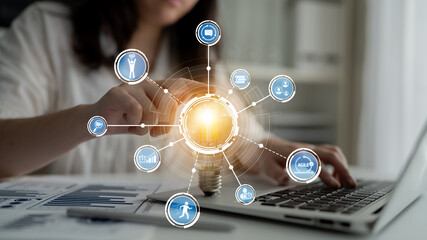 A woman interacts with a laptop, surrounded by digital icons symbolizing technology and innovation, representing modern business and data analysis in a dynamic environment. Crux