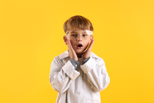 Portrait of surprised little boy in laboratory coat and protective goggles on yellow background. Child and science - Powered by Adobe