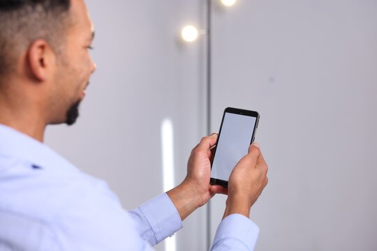 African-american man using modern smartphone in office - Powered by Adobe