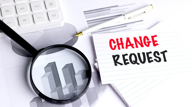 Change request message written on lined card with pen, magnifying glass, calculator and charts on office desk