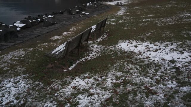 薄っすらと雪が被った湖畔の公園ベンチ