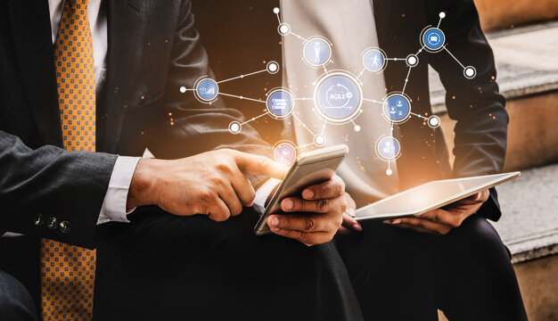 Two business professionals engage in digital communication using a smartphone and tablet, surrounded by technology icons representing data sharing and networking in a modern workspace. Tessel