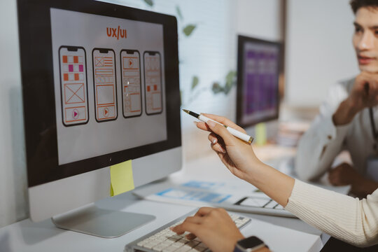 Design team analyzing responsive wireframes for modern smartphone user experience during a creative office meeting - Powered by Adobe