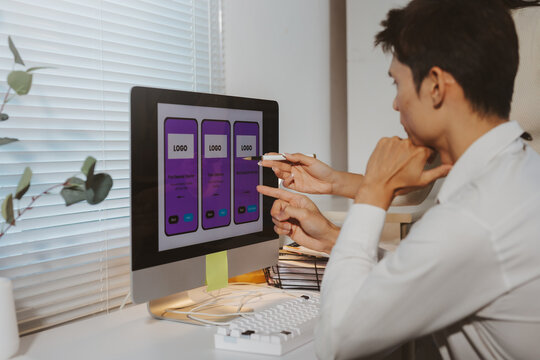 Two designers discussing a mobile application interface and user experience design on a computer screen, pointing at individual elements