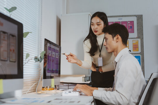 Asian designers working together in office, developing mobile application interface and user experience design on computer screens