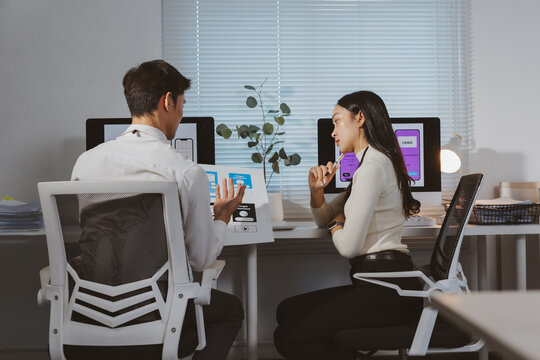 Asian designers discussing user experience and interface mockups for a new mobile application in a modern office meeting