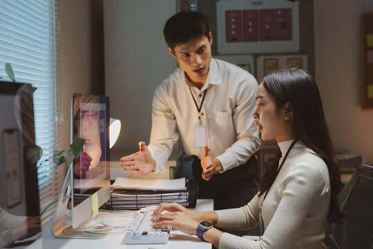 Coworkers collaborating on a UI UX design project, sharing ideas and discussing screens displayed on a computer monitor late in the office
