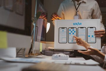 Professional team collaborating on mobile user experience and user interface development, analyzing wireframes and design mockups