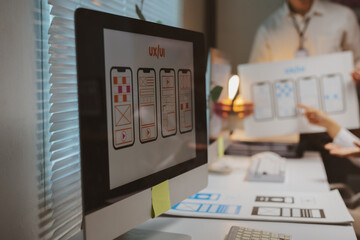Designers collaborating on a meeting explaining responsive wireframes and User Experience - UX - for a mobile application development project