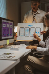 Two UX UI designers working together, discussing wireframes for a new mobile application development project in an office