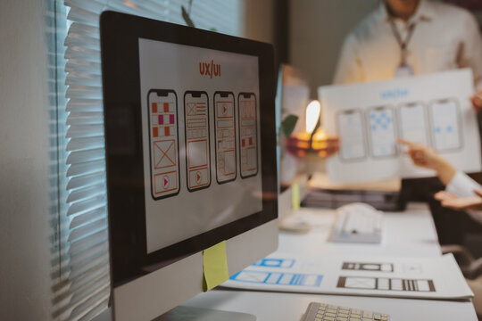Designers collaborating on a meeting explaining responsive wireframes and User Experience - UX - for a mobile application development project