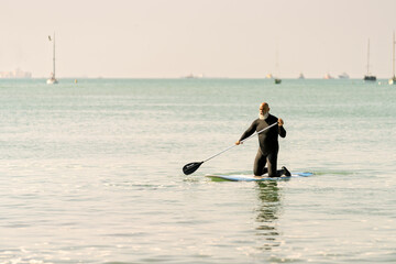 Senior man paddleboarding on calm ocean water
