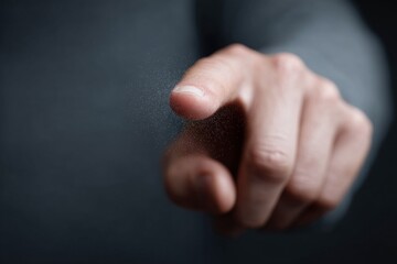 Hand pointing a finger towards the camera, close up shot with dark, blurry background and glowing particles. Hand pointing forward