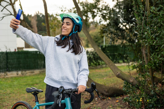 Young woman taking selfie with smartphone while riding bicycle - Powered by Adobe